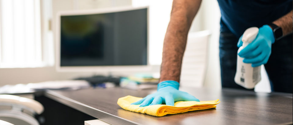 man cleaning counter with gloves and disinfectant