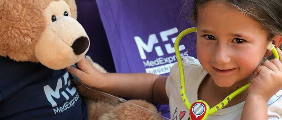 little girl holding a stethoscope to Sniffles the teddy bear's chest