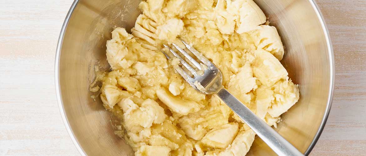 mashed bananas in bowl with fork