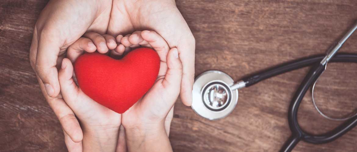 Adult hands cupping a child's hands holding a red heart