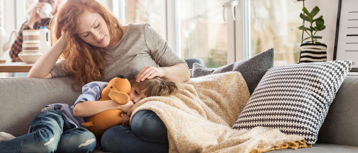 child resting on woman's lap on a couch