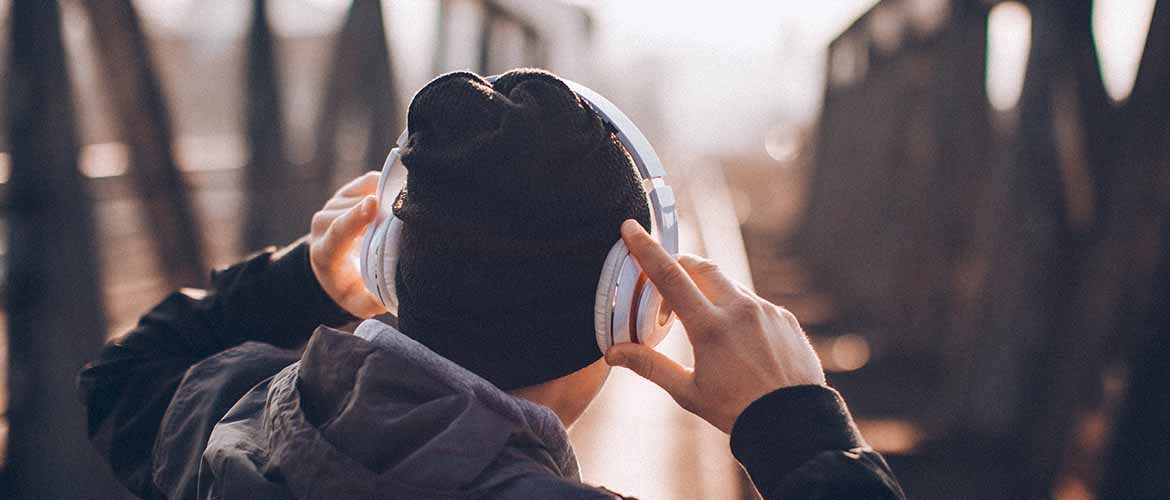 a person on a bridge holding a pair of headphones on his ears