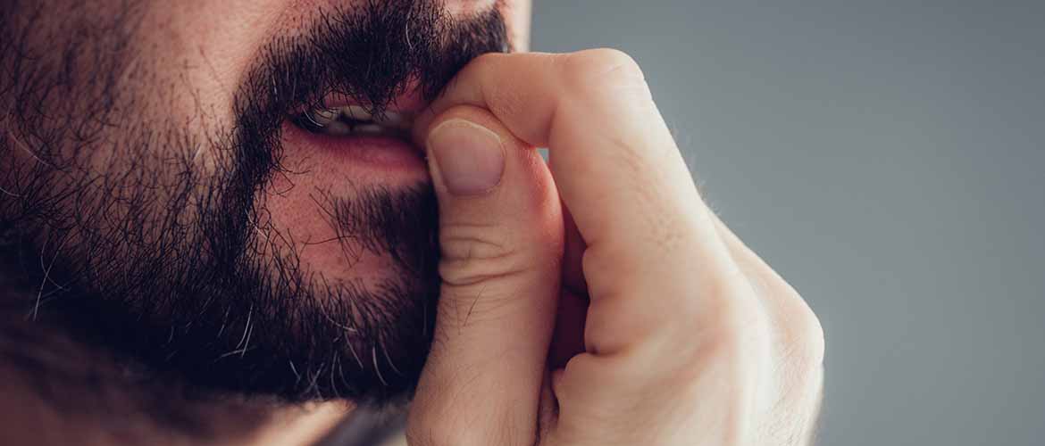 close-up of a bearded man chewing on his finger nails