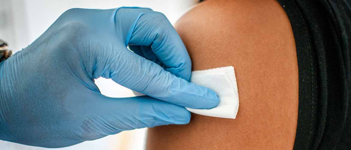 A doctor disinfects a patient's skin before administering a vaccination