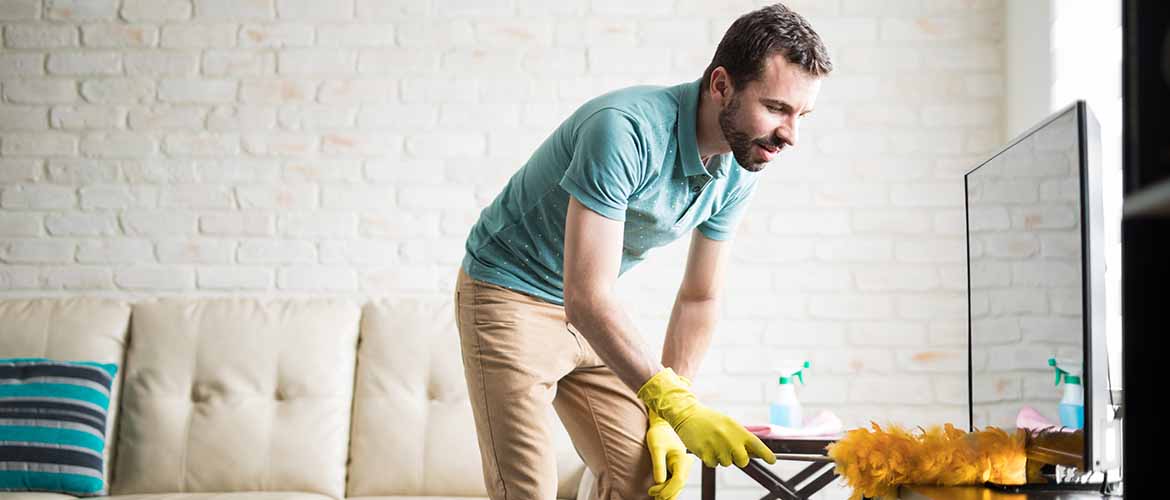 a young man dusting his apartment