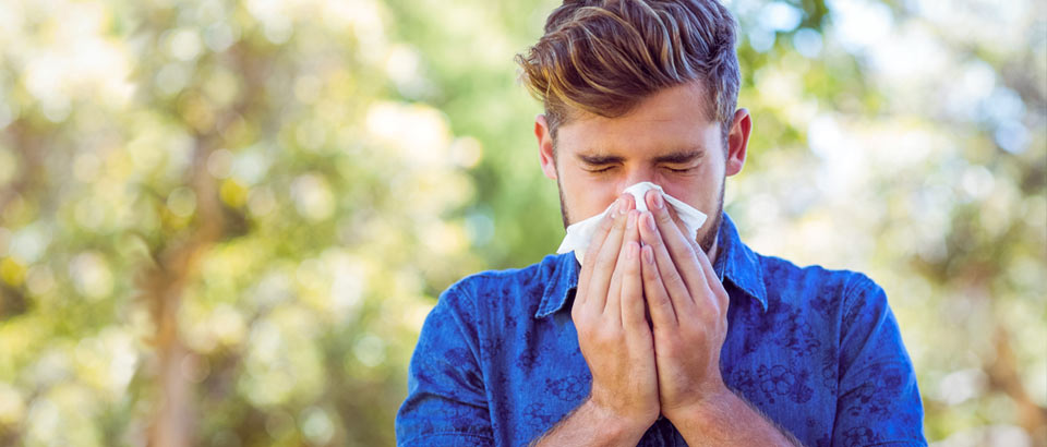 young man sneezing into a tissue