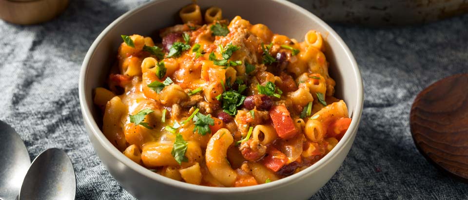 bowl of chili mac and cheese sitting on a table