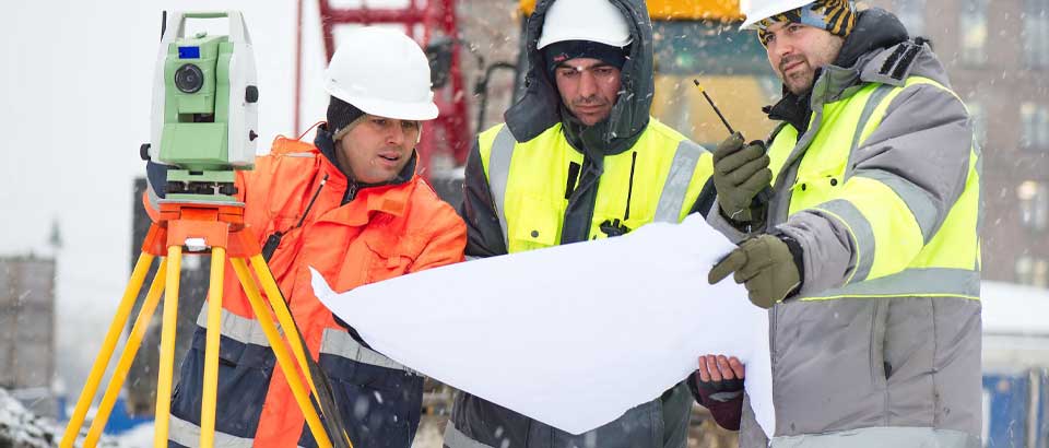 employees looking at papers while outside in the snow