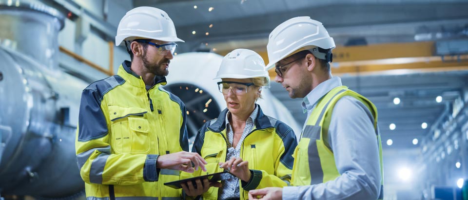 employees with hard hats reviewing paperwork together