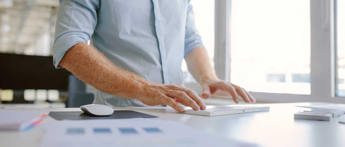 man typing at standing desk