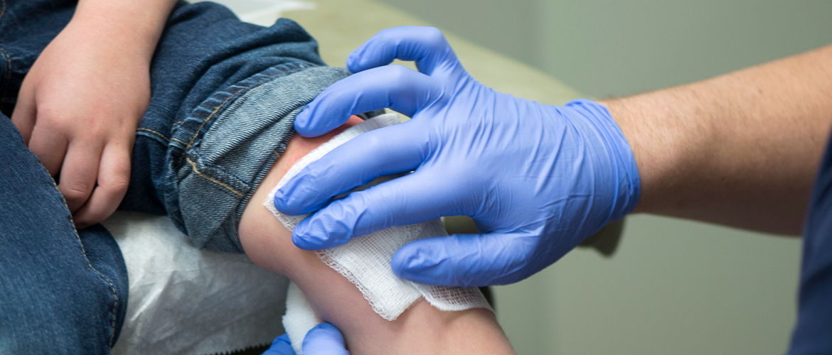 MedExpress provider uses a piece of gauze to clean a child's scraped knee