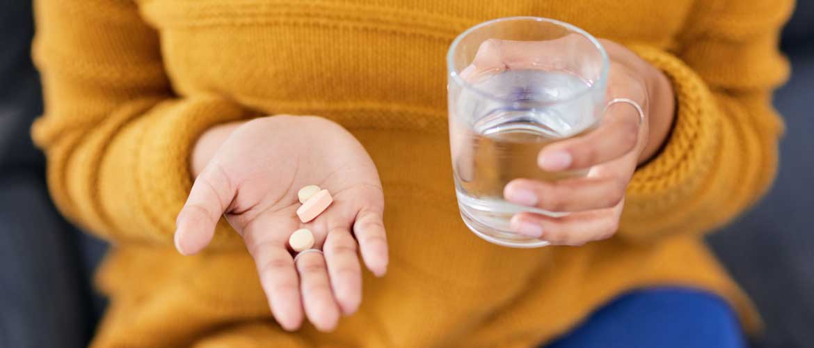 woman holding glass of water and antibiotics medicine