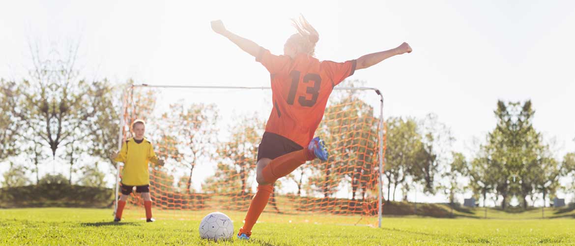 A soccer player about to kick the ball into the goal