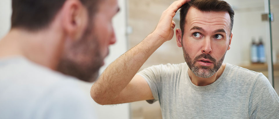 man looking at hair in mirror