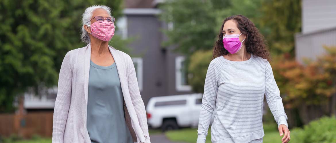 a woman and her mother wearing face masks while taking a walk outdoors
