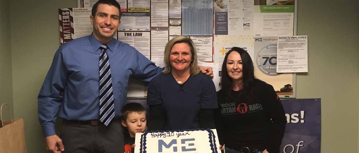 Tracie Dilliner holds a cake celebrating her 10th work anniversary with MedExpress while surrounded by some of her co-workers