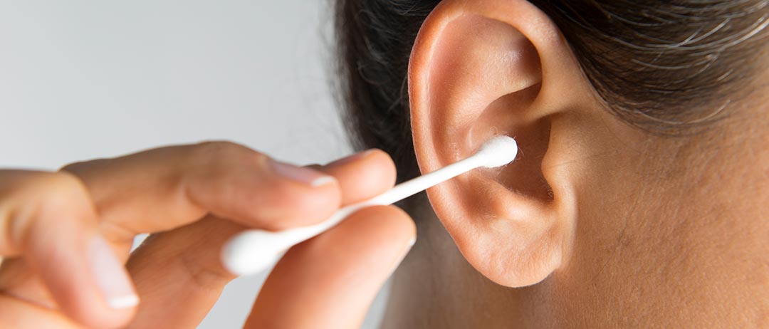 a woman using a Q-tip to clean her ear