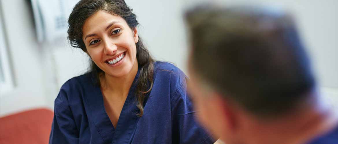 two medical professionals dressed in scrubs sit at a table while conversing