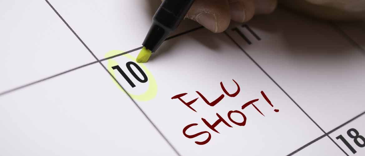 a person circling the number ten on a calendar with the word Flu Shot written in red