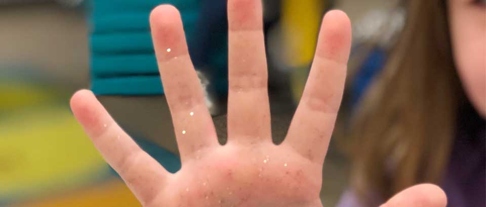 a child showing their hand with glitter all over it