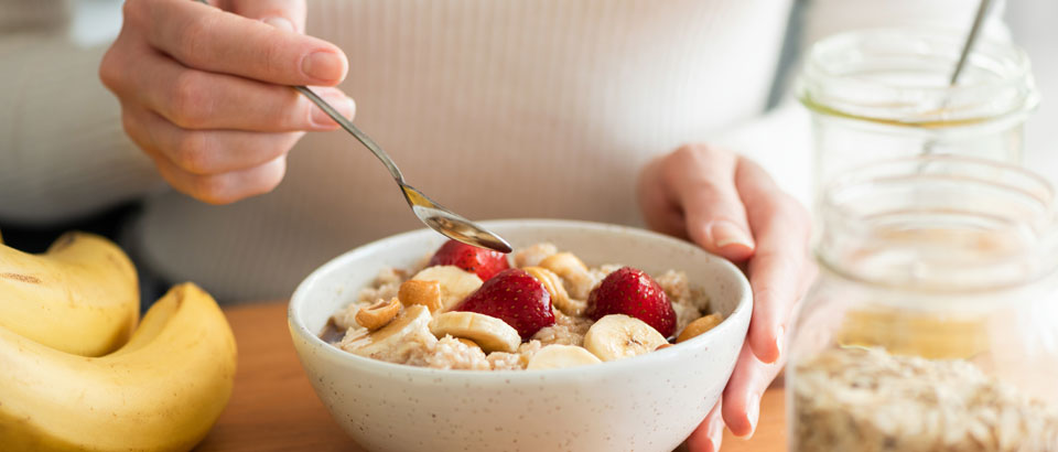 woman holding a spoon while eating oatmeal with berries