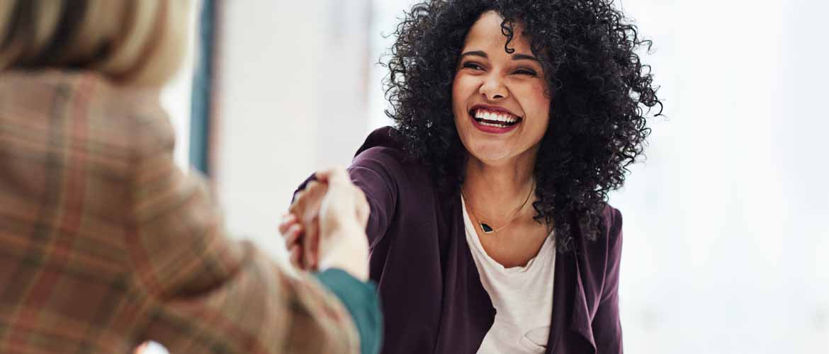 smiling woman shaking hands with another woman