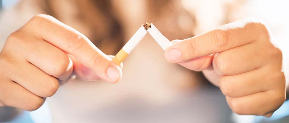 person breaking a cigarette in half