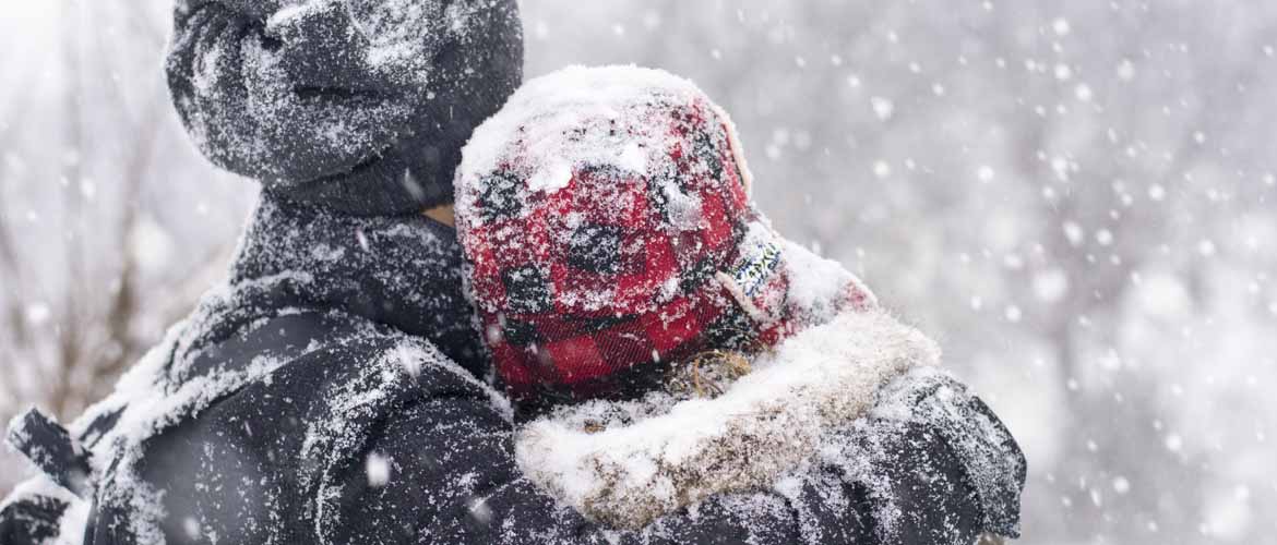  un hombre y una mujer de pie afuera mientras nieva