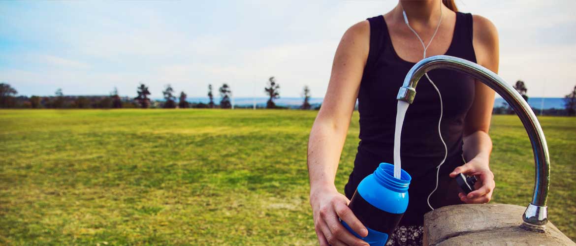 woman filling up a water bottle at an outdoor water fountain