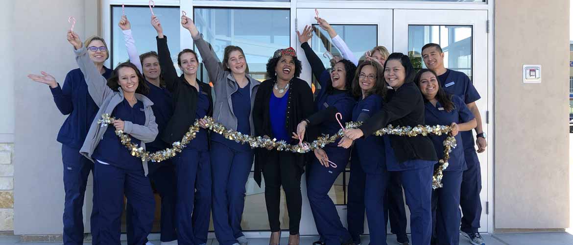 The staff of a MedExpress center standing outside the building with their hands up cheering