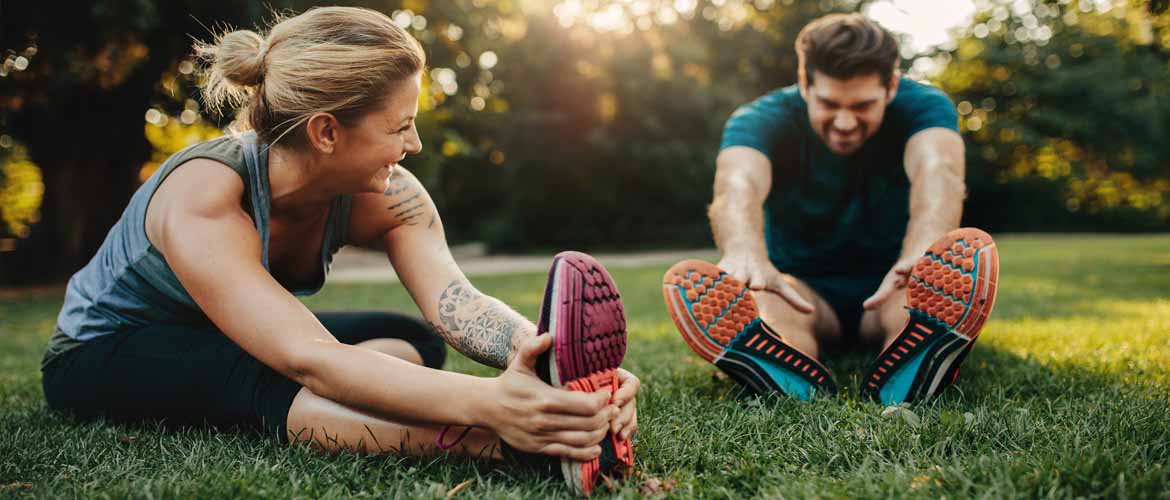 a woman and man outside stretching before a run