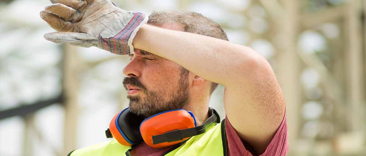 a construction worker wiping sweat from his forehead
