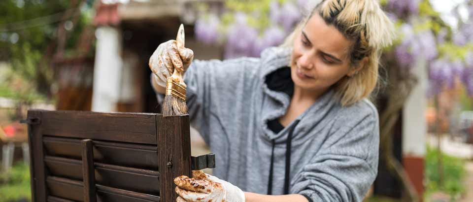 a woman staining a piece of furniture