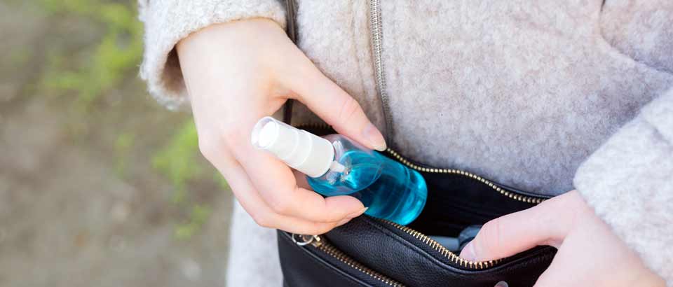 a woman putting a bottle of hand sanitizer in her purse