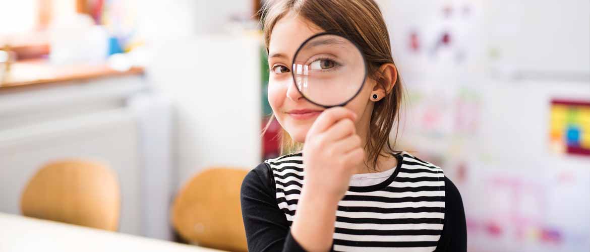 little girl looking through a magnifying glass