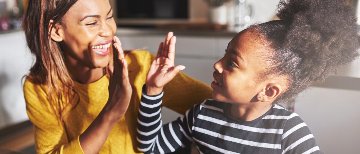 African American mother and child giving each other a high five and smiling