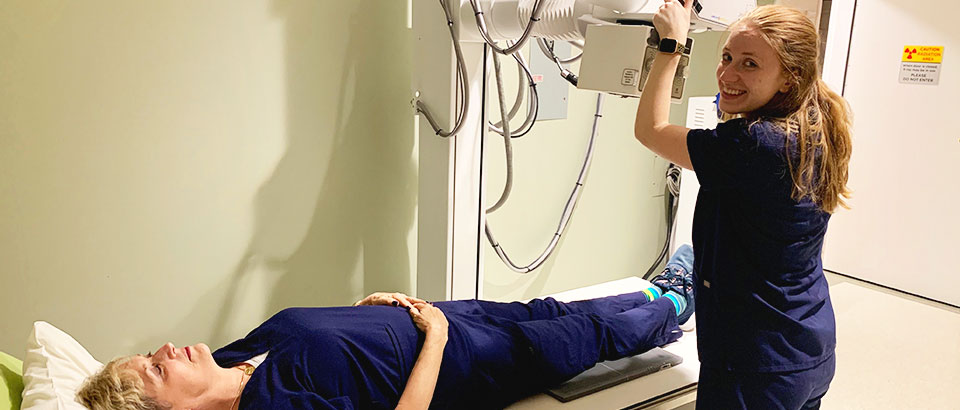 Kaitlin Berger situating X-ray equipment while her coworker lays on a procedure table