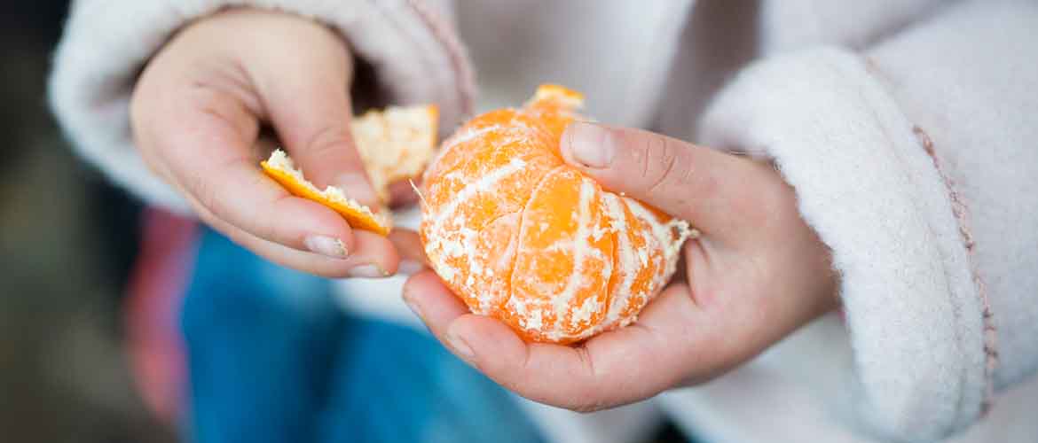 a woman peeling a clementine for a quick snack on the go