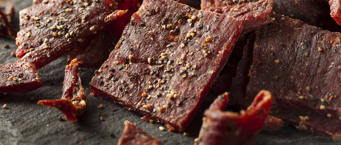 a pile of dried, peppered beef jerky cut in strips for a grab and go snack