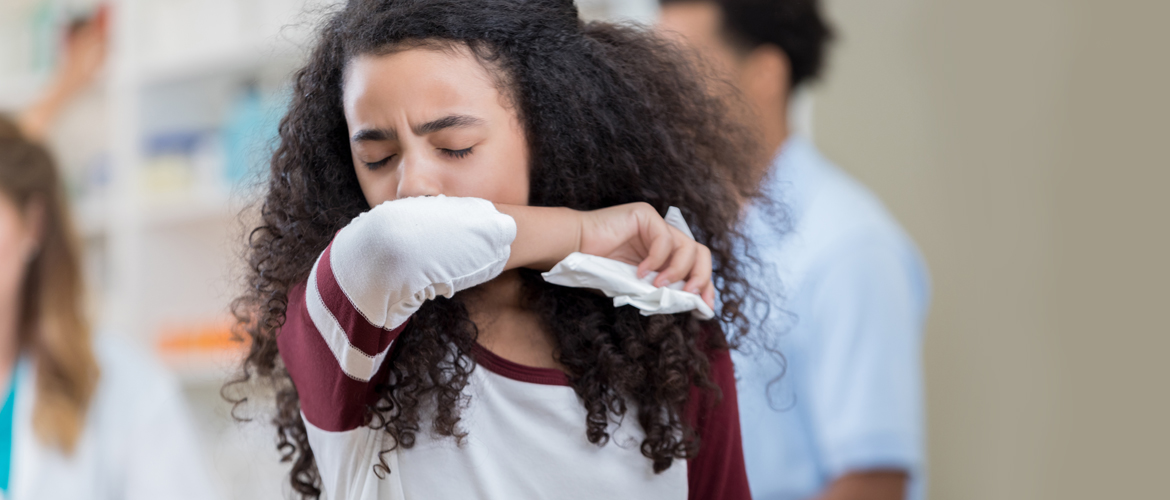 girl sneezing into arm