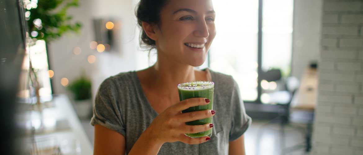 persoon die een groene smoothie uit een glas drinkt