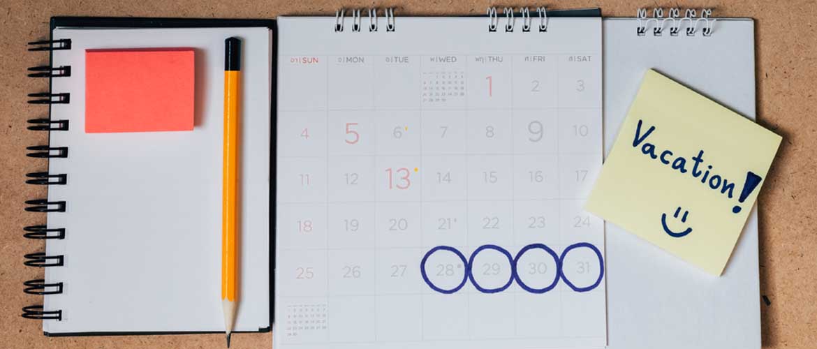 calendar sitting on desk with days circled and a sticky note that says vacation
