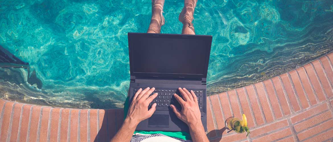 man working on computer at the pool