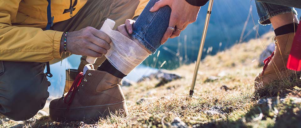 a hiker bandaging another hiker's injured leg