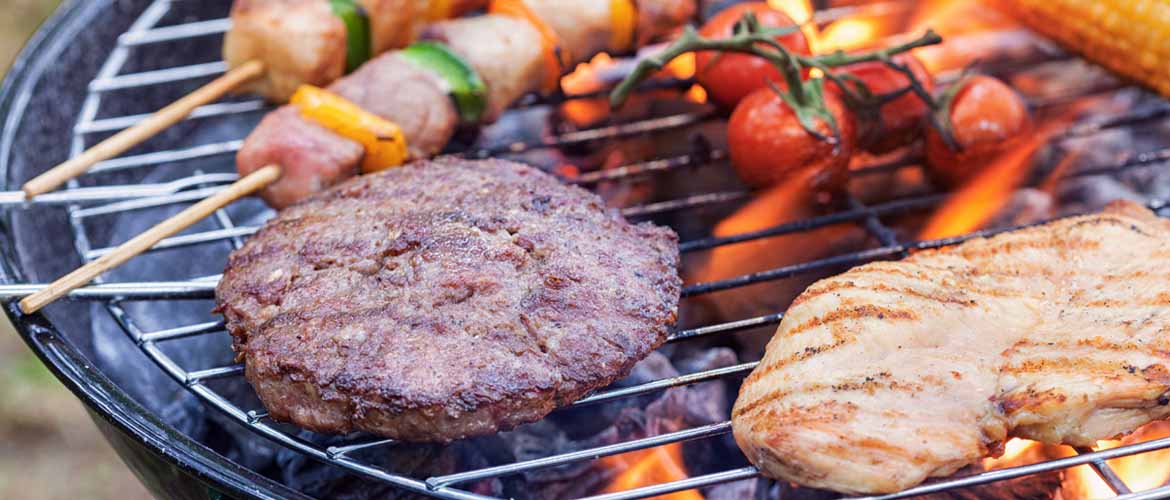 a piece of beef, chicken, and several shish kabobs cooking on a grill