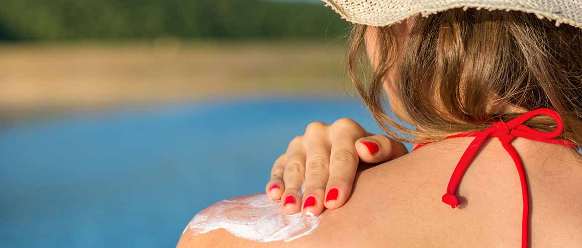 woman rubbing sunscreen on her shoulder