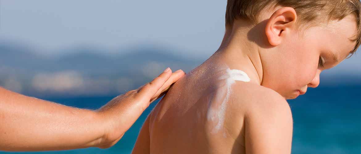person rubbing sunscreen on a little boy's back