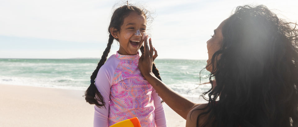 person applying sunscreen to young childs face