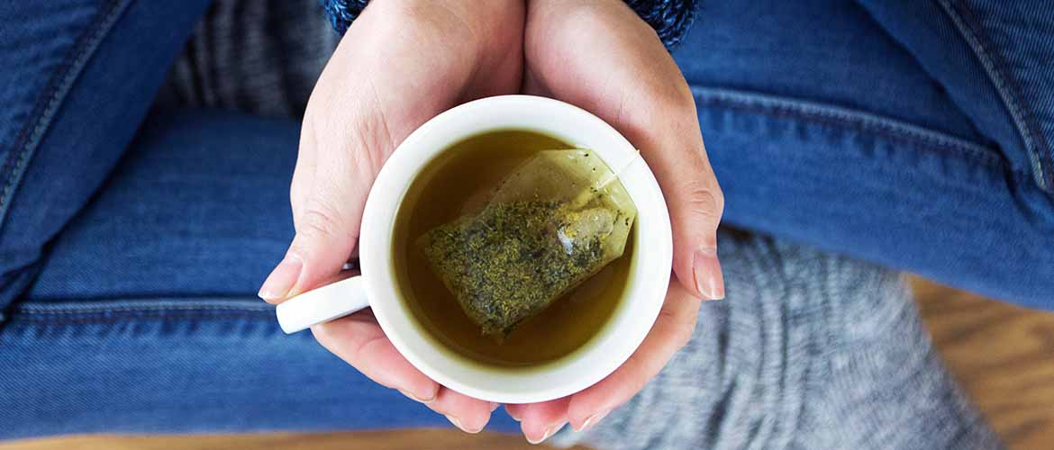 a person holding a cup of green tea