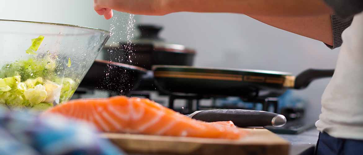 a person salting a piece of salmon